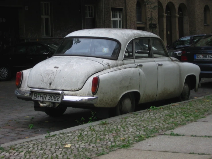 an old - fashioned car is parked on the sidewalk by some other cars