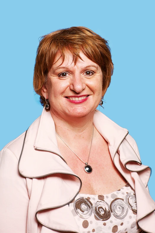 an older woman wearing a tan top and smiling at the camera