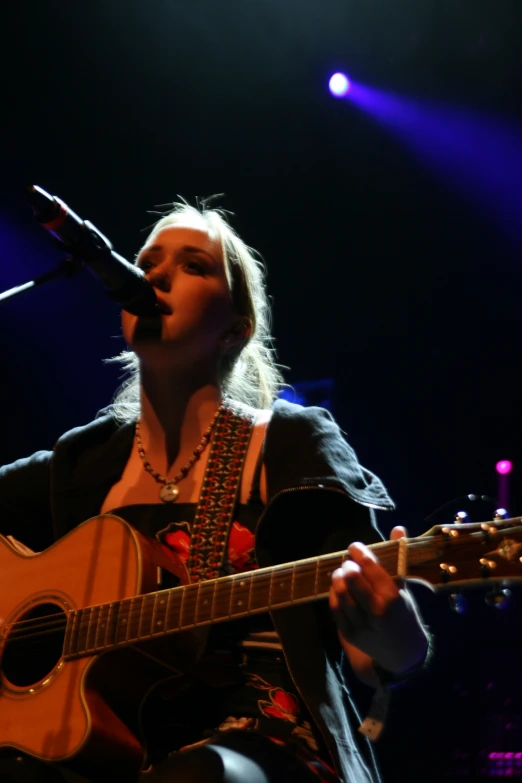 a woman playing guitar in front of a microphone