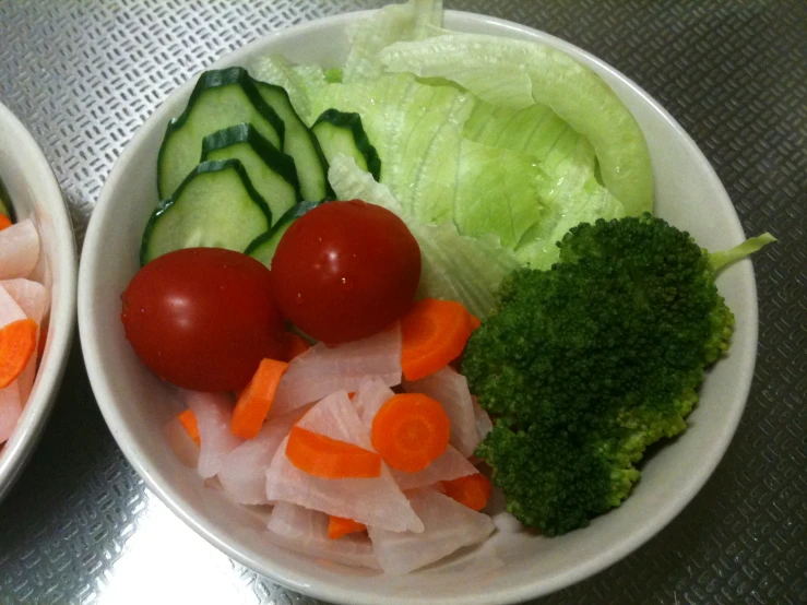 two bowls full of veggies are set on a table