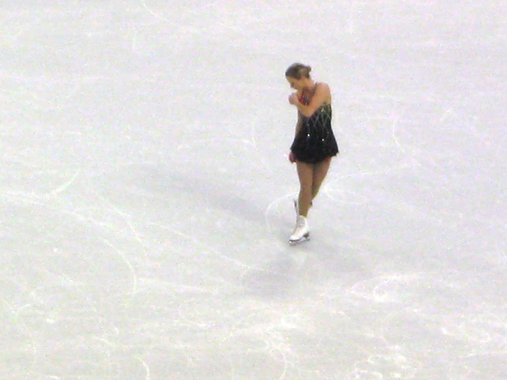 a female figure skater wearing black is skateboarding on ice