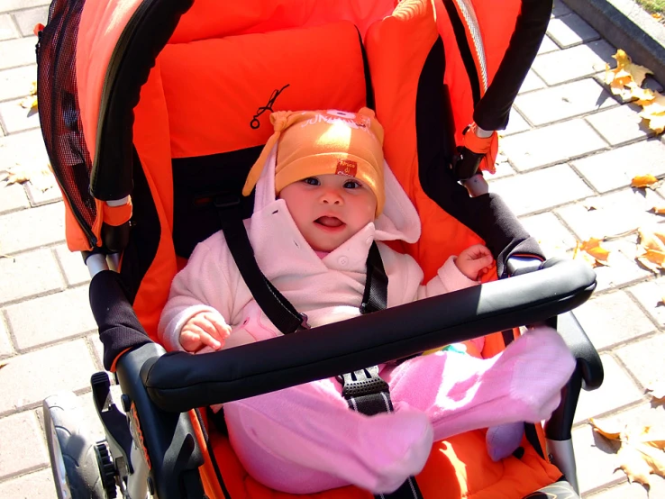 small baby in pink outfit sitting in stroller