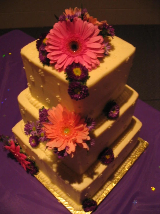 a three layered wedding cake with flowers on top