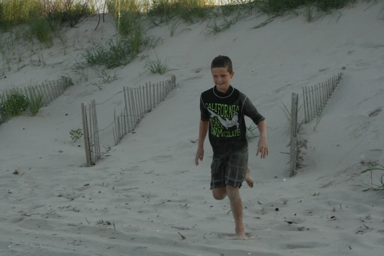 there is a boy walking in the sand