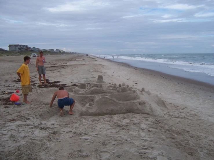 the three children are playing in the sand near the ocean