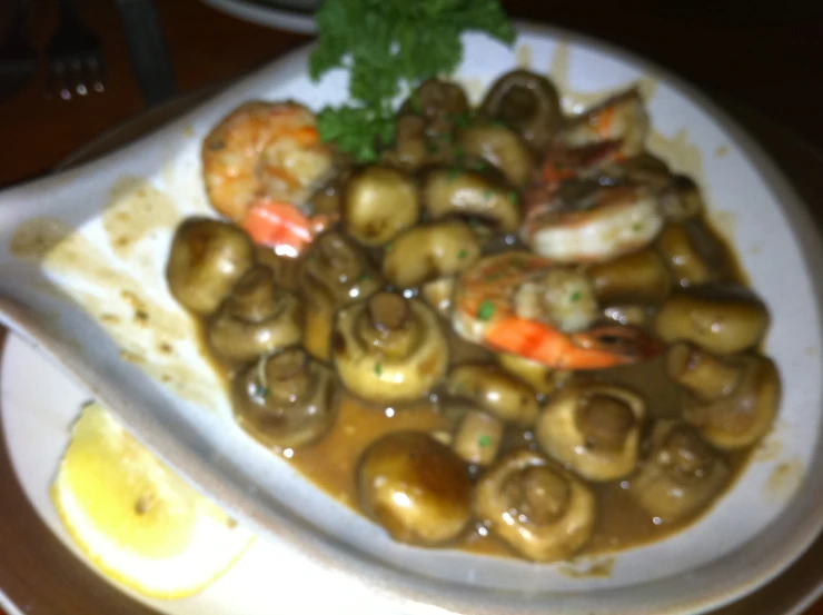 a white plate of food with shrimp, mushrooms, and potatoes on a table