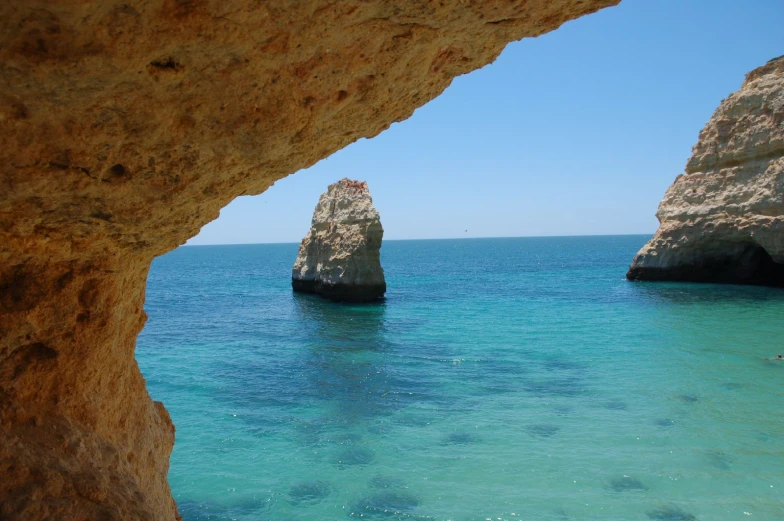 a beautiful blue ocean with some rocks sticking out