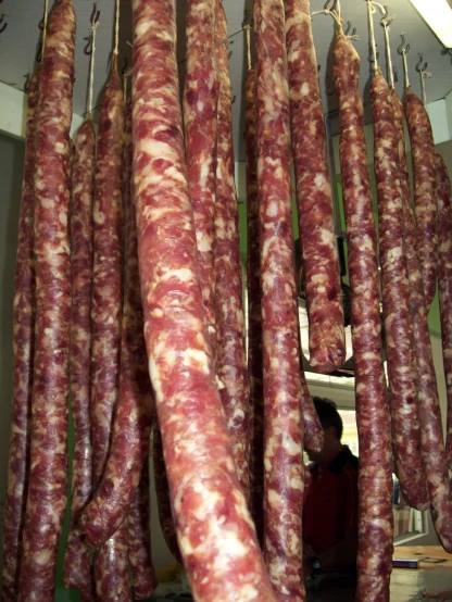 a large group of different type of sausages hanging on hooks