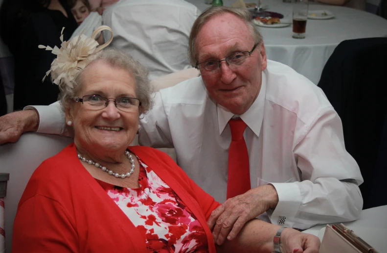 an older couple in red sitting together at a formal function