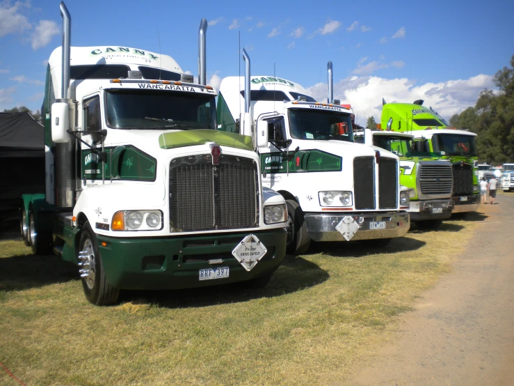 two big rig trucks parked in the grass