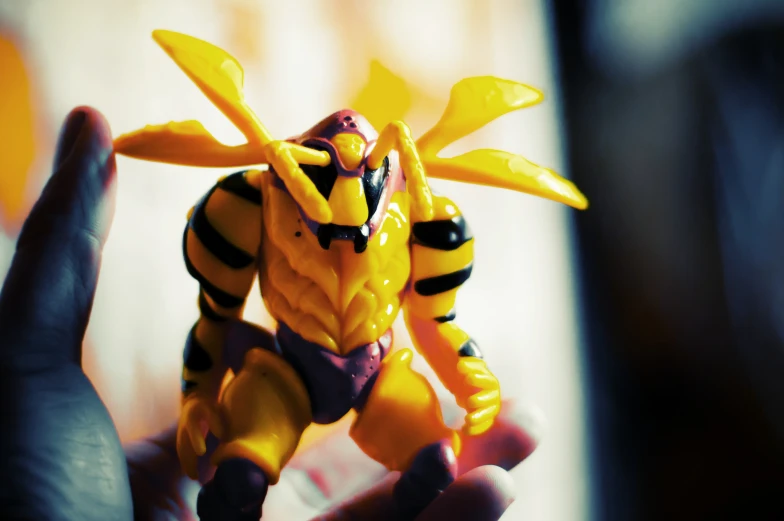 a small yellow action figure that is posed for a po