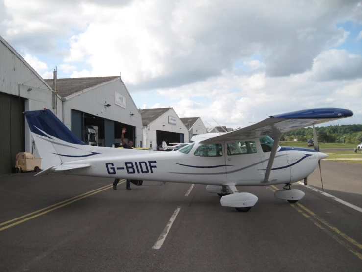 an older style small plane sits parked near a storage area