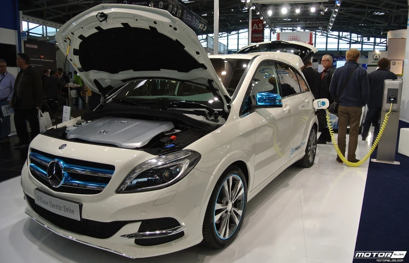 a white car with its hood open parked in a room