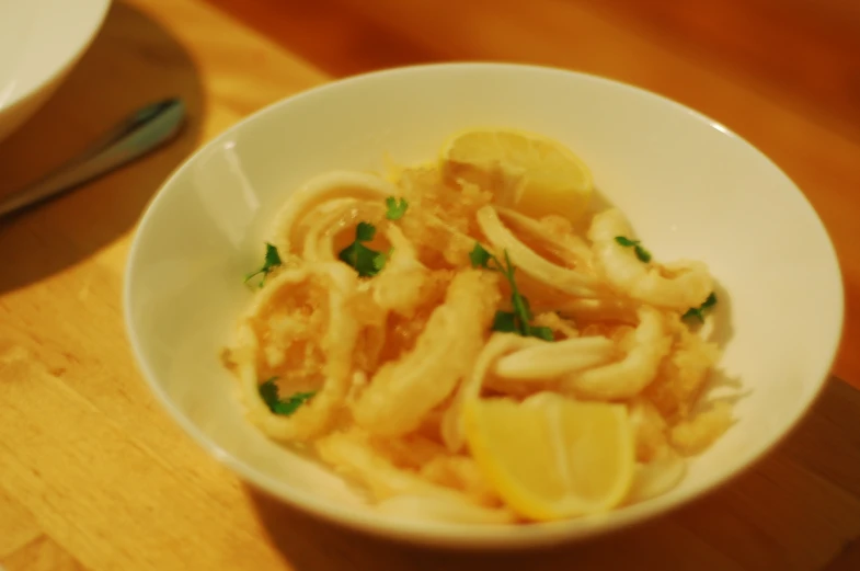 a white bowl full of cooked food, with garnish