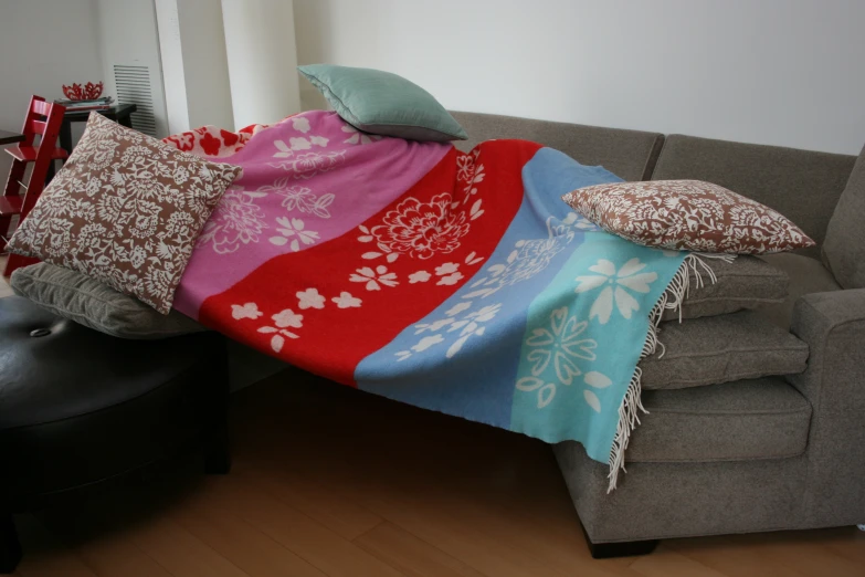 a blanket sitting on top of a sofa covered in pillows