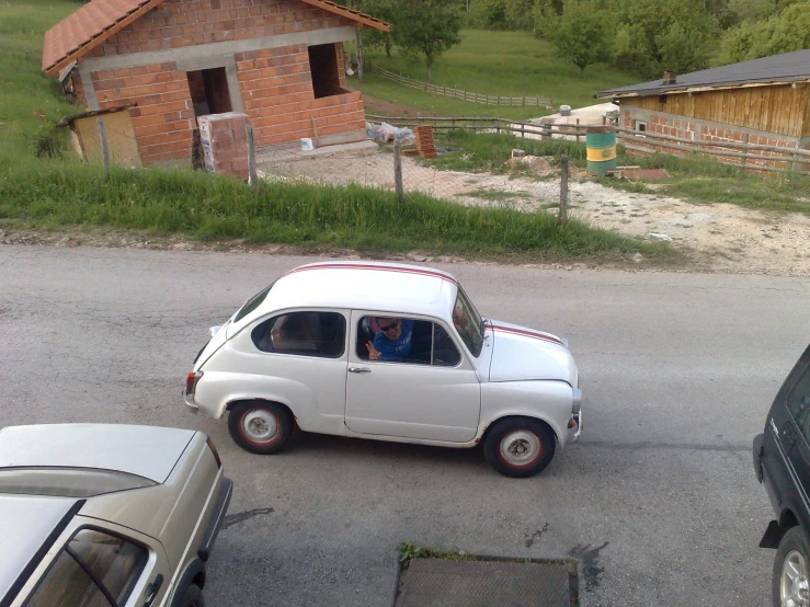 an old - fashioned white car in a parking lot is near two other cars