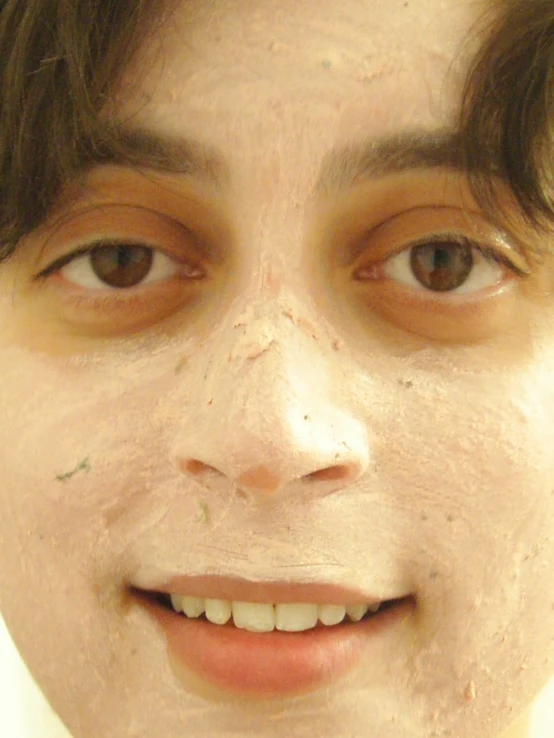 a person wearing clay covered on their face and making funny face