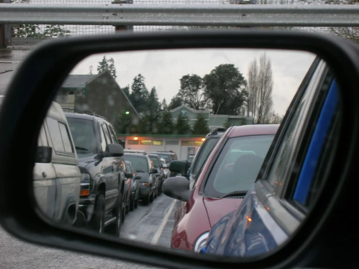 several vehicles parked in a line up and reflected in a mirror