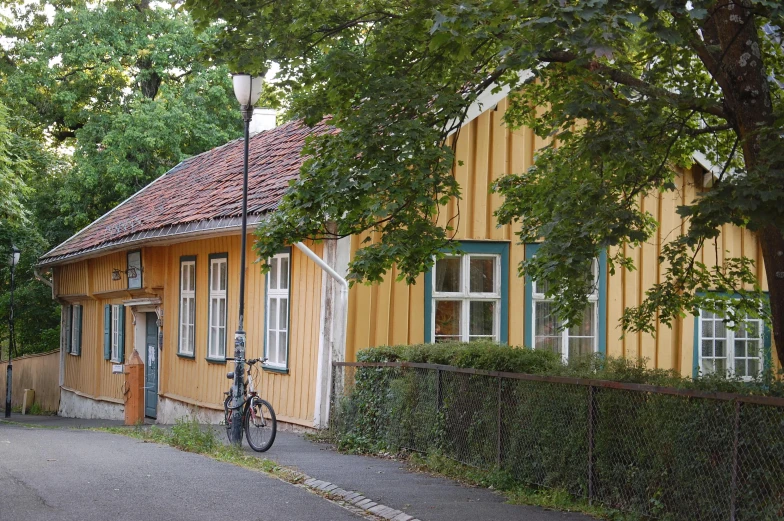 an old house in the woods behind a fence and a bicycle parked near it