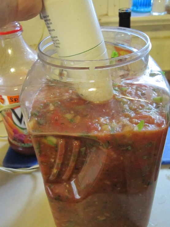 a hand is using a drink bottle to fill a container