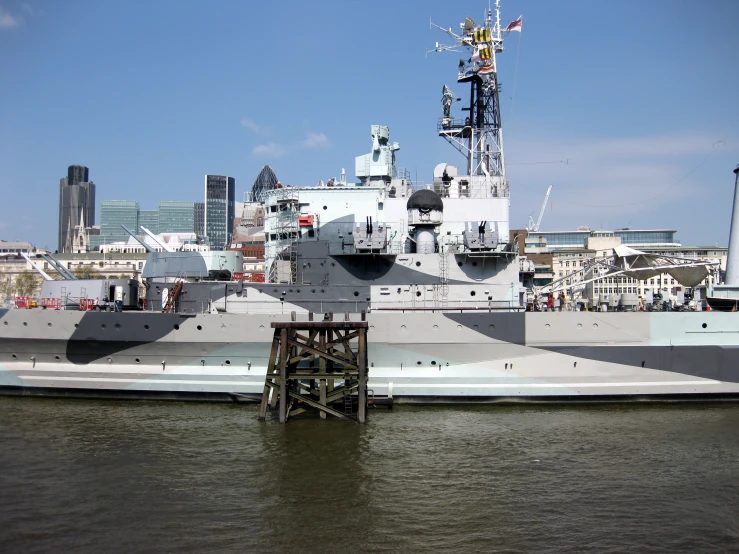 a large battleship in water with a city in the background