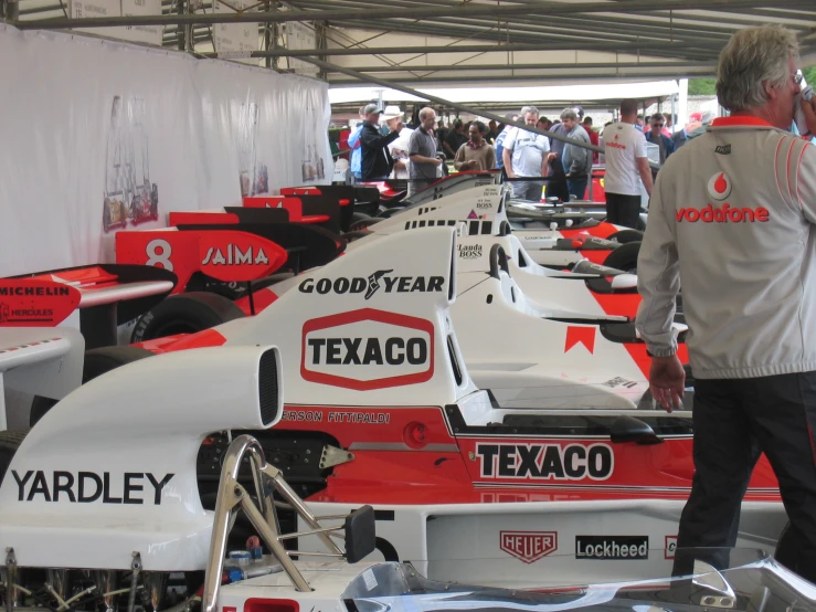 people observing some race cars on display for spectators