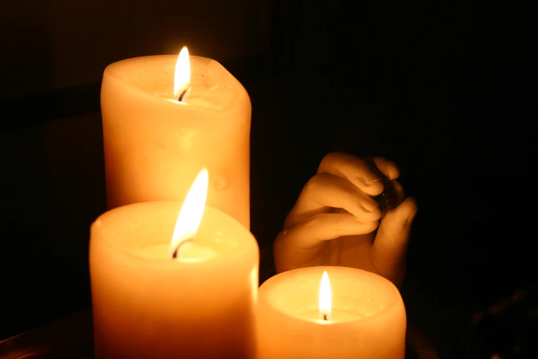 the woman is sitting with her hands on a group of lit candles