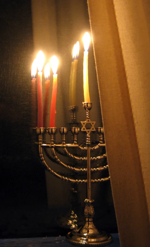 lit candles are sitting in a silver menorah