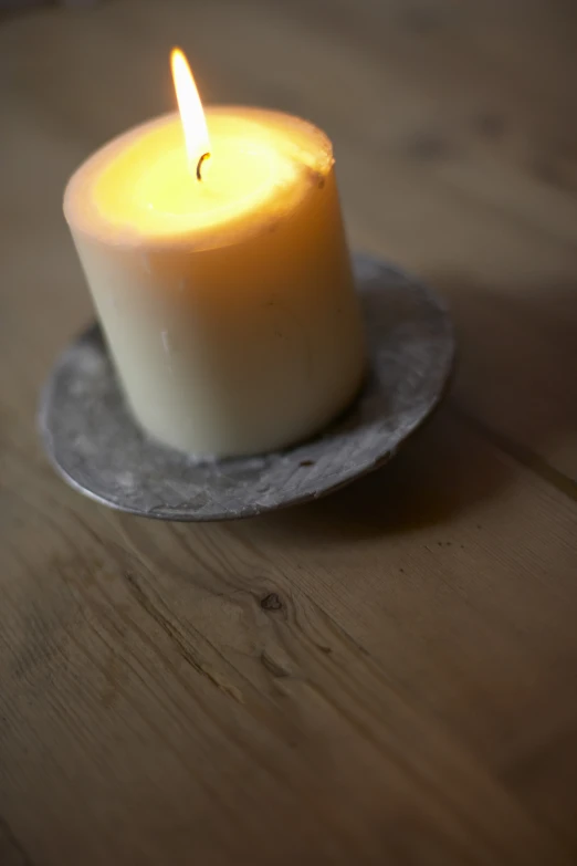 a white candle burning brightly on a plate