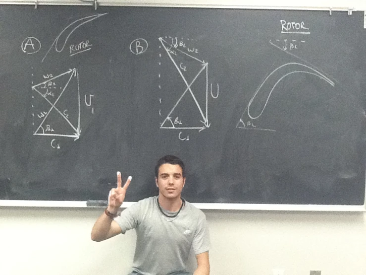 man in gray shirt pointing at the blackboard