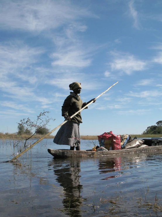 a woman stands in a canoe and looks into the distance