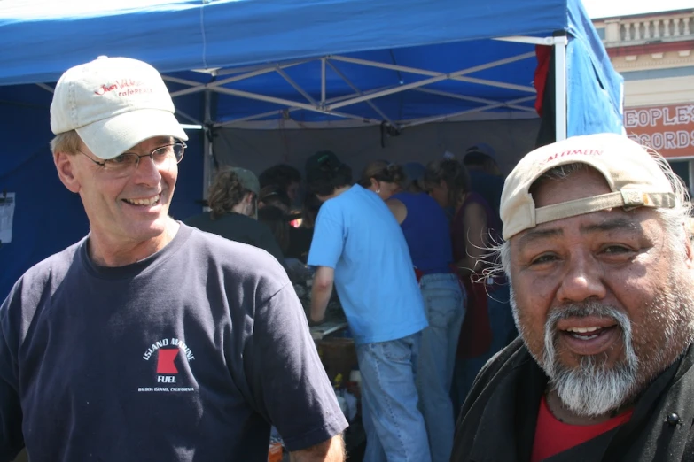 the two older guys are having fun under the blue tent