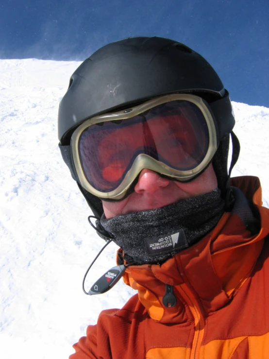 a man in goggles, an orange jacket and ski gear