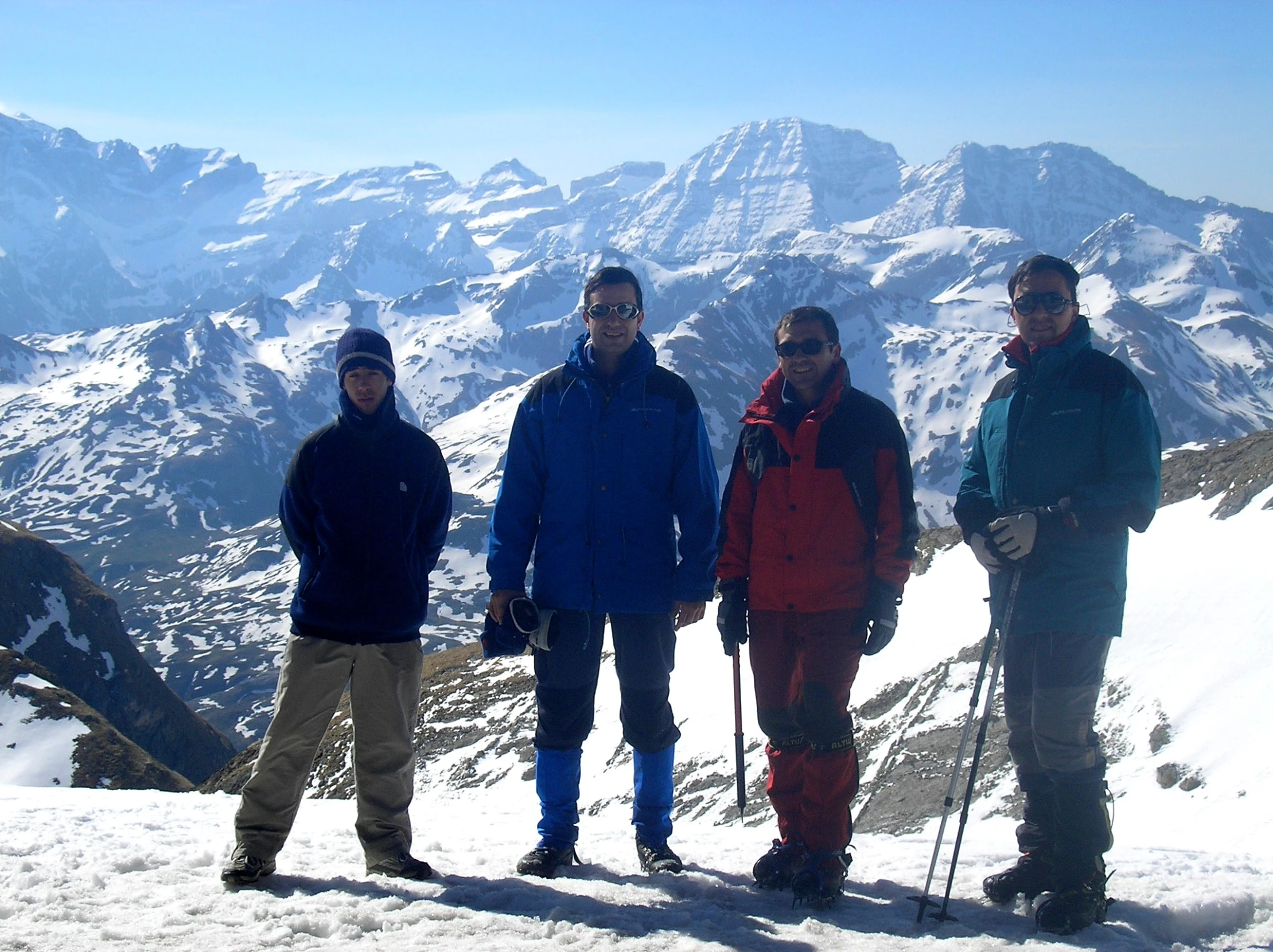 three skiers pose on a snowy mountain top