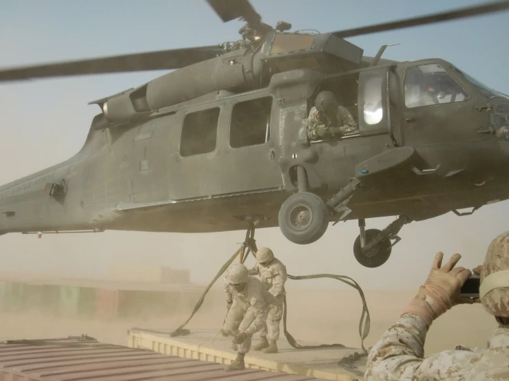 a helicopter with four soldiers surrounding it and one is on the ground