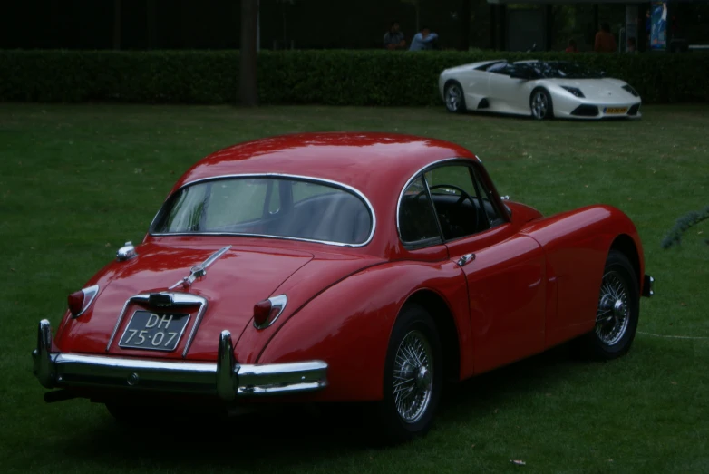 two classic cars sitting in a grassy area