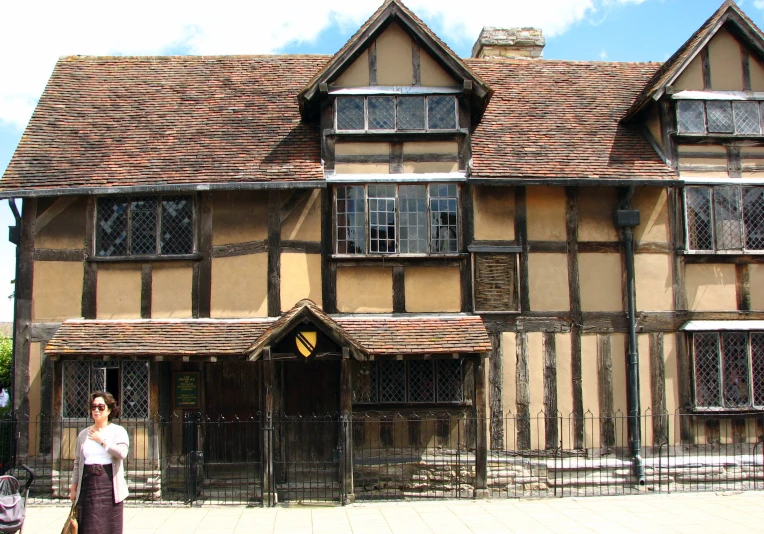 woman standing in front of brown and black house with tall windows