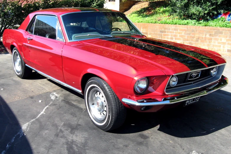 an old mustang with chrome rims parked in a parking lot