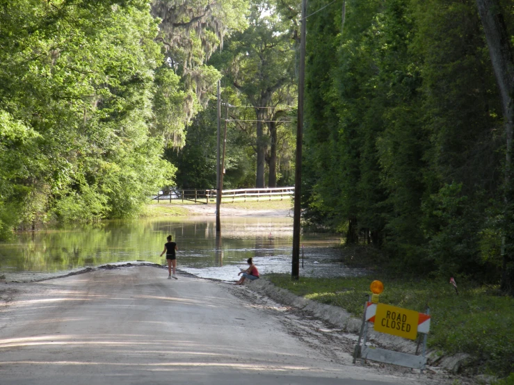 a flooded road with people and a sign