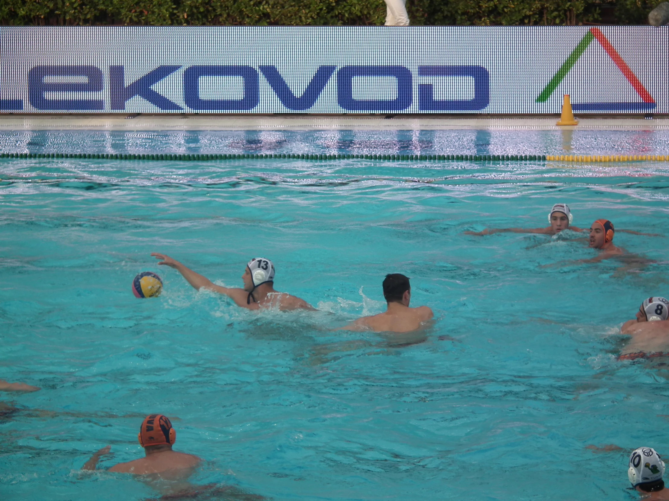 four people swimming in an indoor pool one is catching the ball