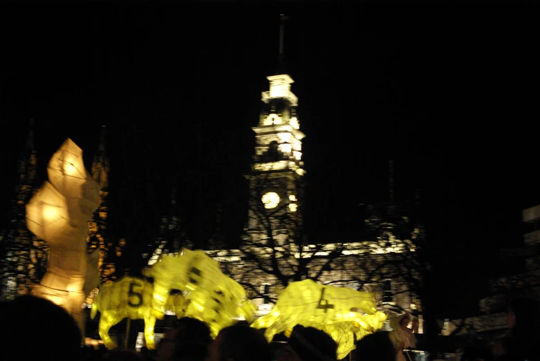 people standing in front of a lighted building with clock tower