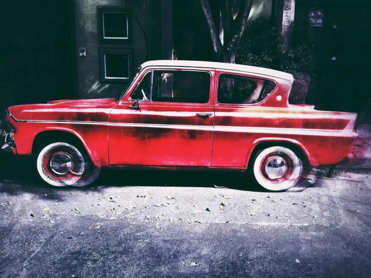 an old red car parked on a street