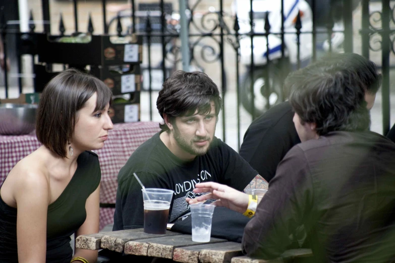 the girl with the black dress on is drinking a soda with a man looking on