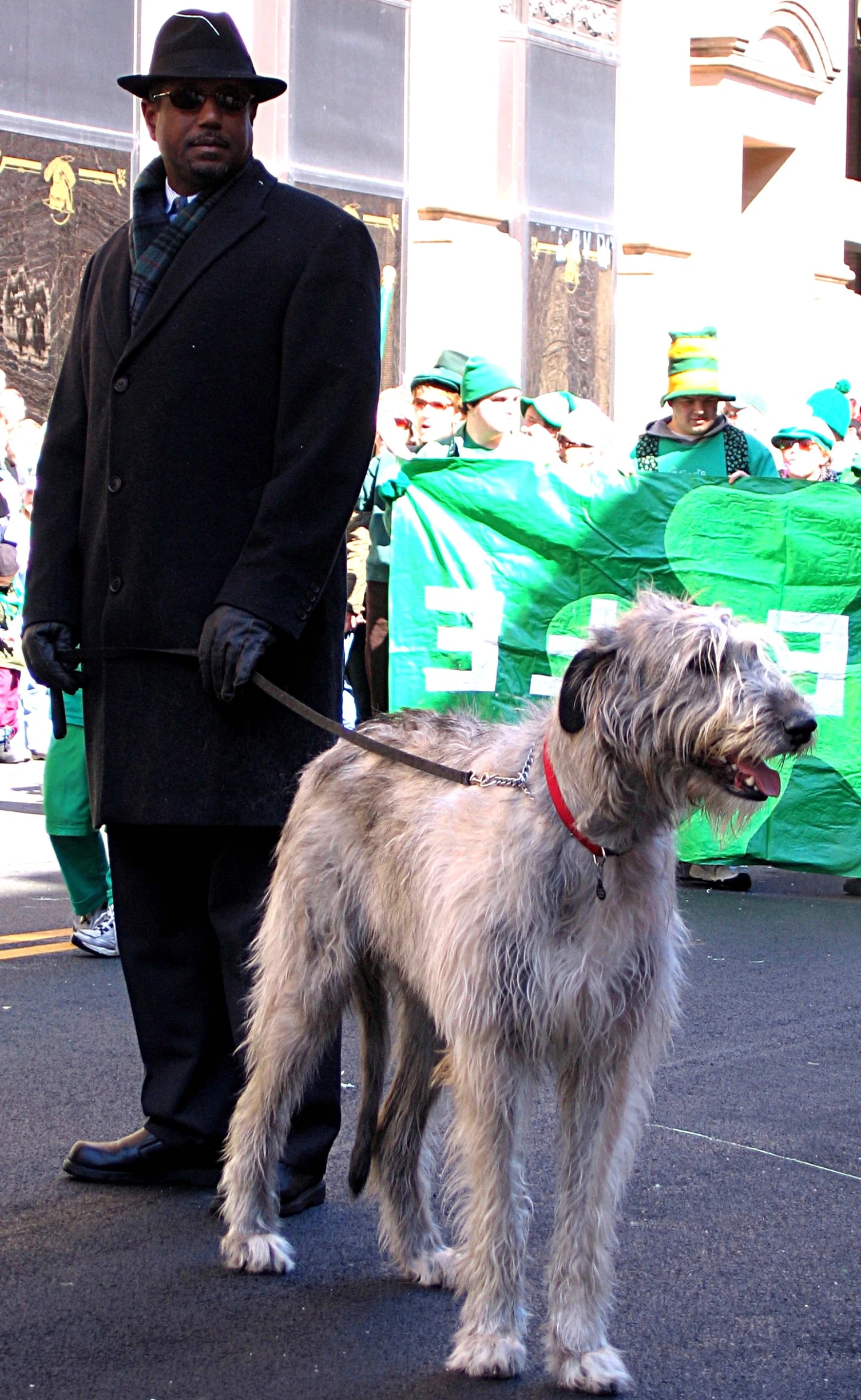 a man in a top hat walking his dog down the street