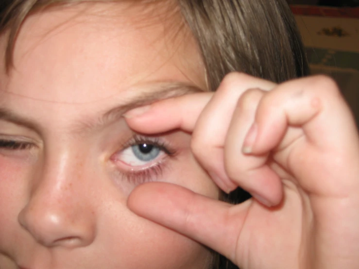 a  is touching her left eye and placing an item in the center