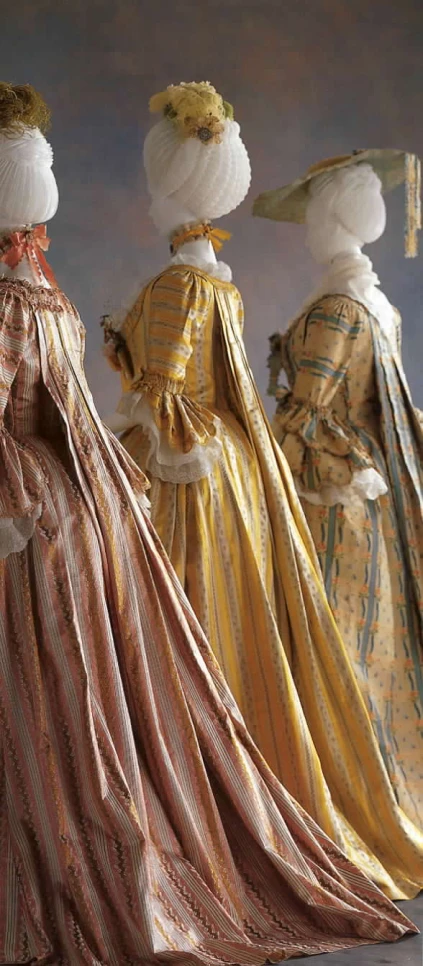three fancy dresses with white bonnets and red and yellow stripe dresses