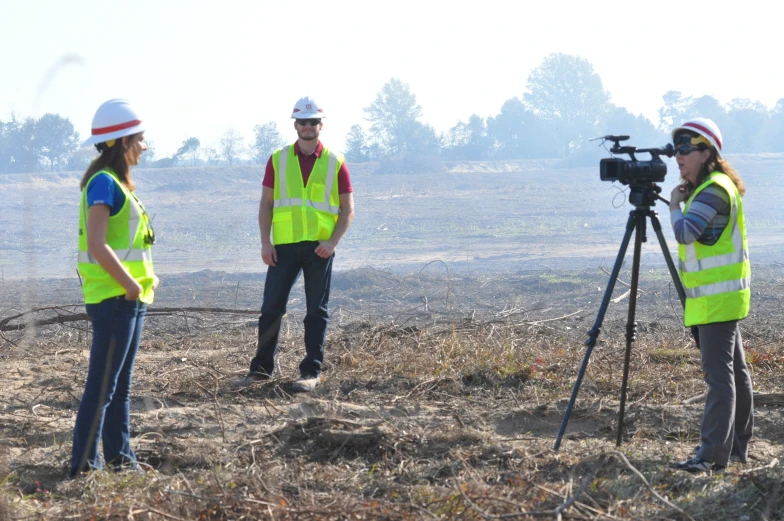 people in safety vests with camera equipment