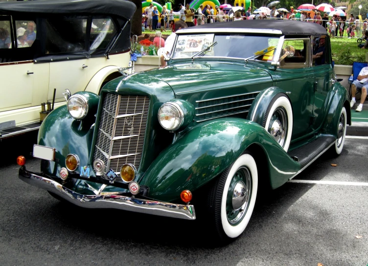 an old green car is parked near other cars in the parking lot