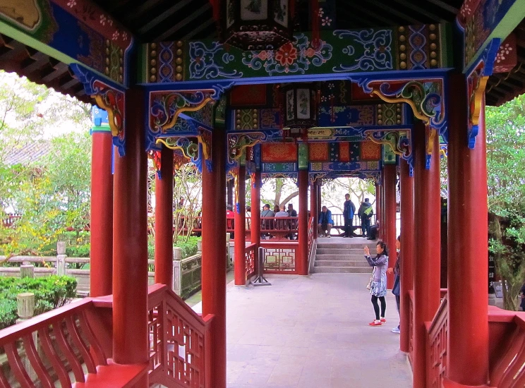 a person stands under an ornate colored wooden archway