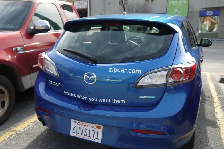the back end of a blue vehicle with a car tag on the hood